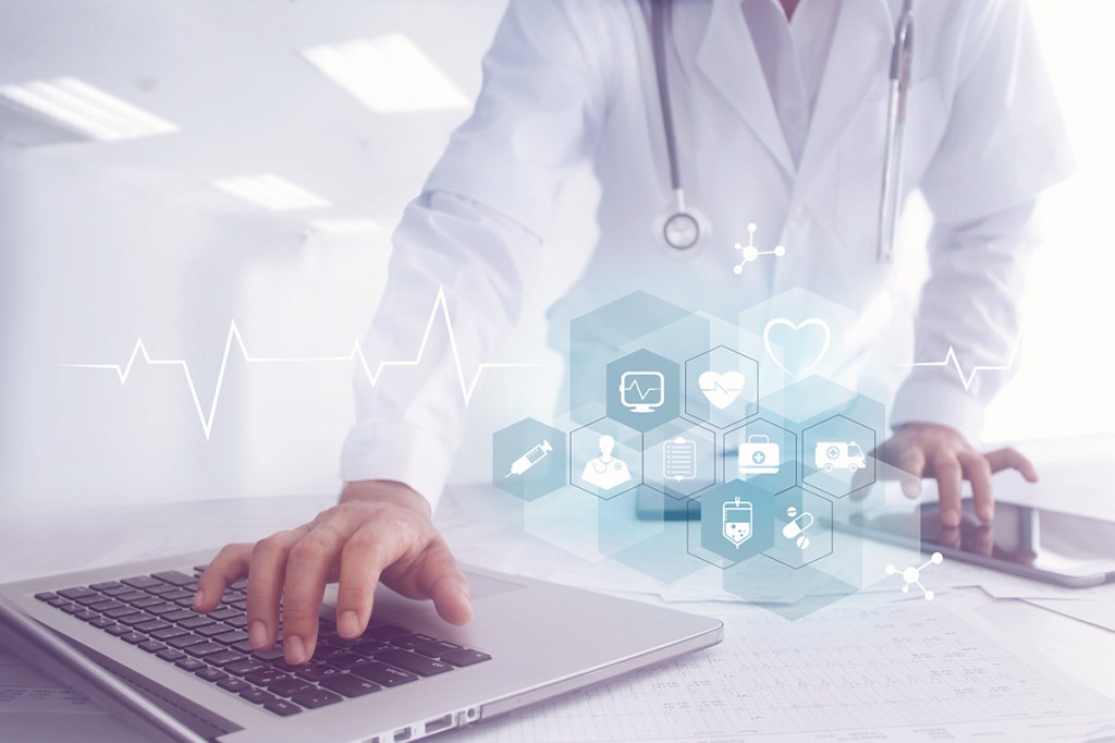 Clinician at a laptop with medical icons over the desk