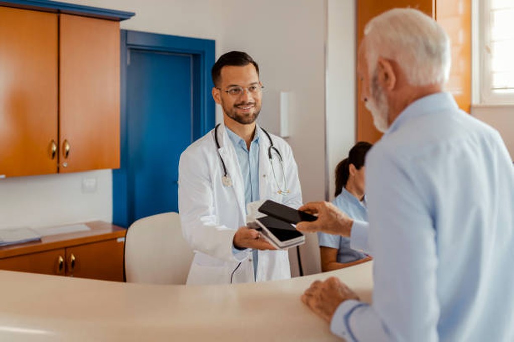 Doctor handing a tablet to a patient at the clinic desk